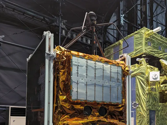 The image shows a large satellite in a large room with a lot of equipment, including a satellite on...