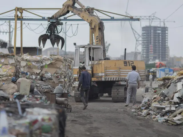 The image shows a group of men walking down a dirt road next to a pile of trash, with an excavator...
