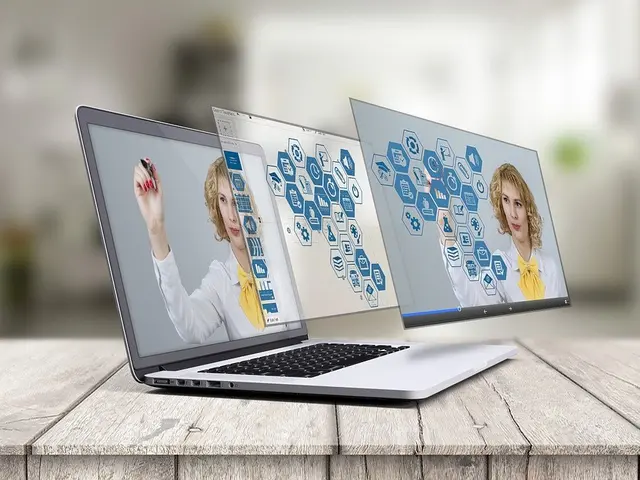 The image shows two laptops sitting on top of a wooden table, with a blurred background. On the...